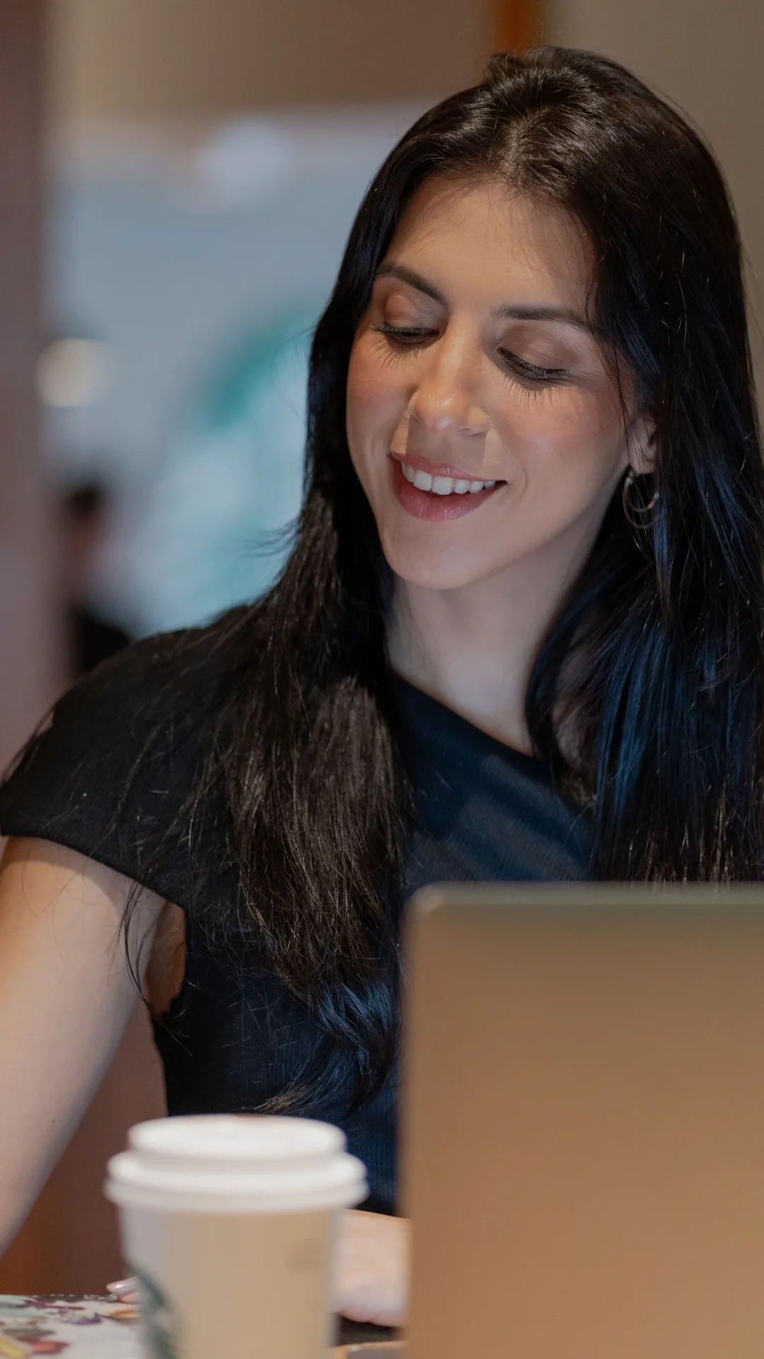 Consultora sorrindo enquanto trabalha no notebook